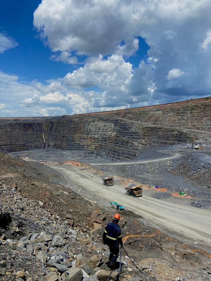 Field engineer surveying active open-pit mining operations